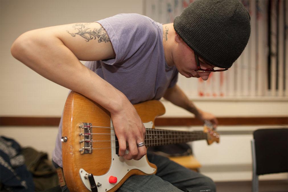 Young person wearing black beanie hat playing the guitar