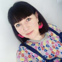 Steph, our consellor, a person with dark shoulder length hair wearing red earrings and a floral top and dungarees