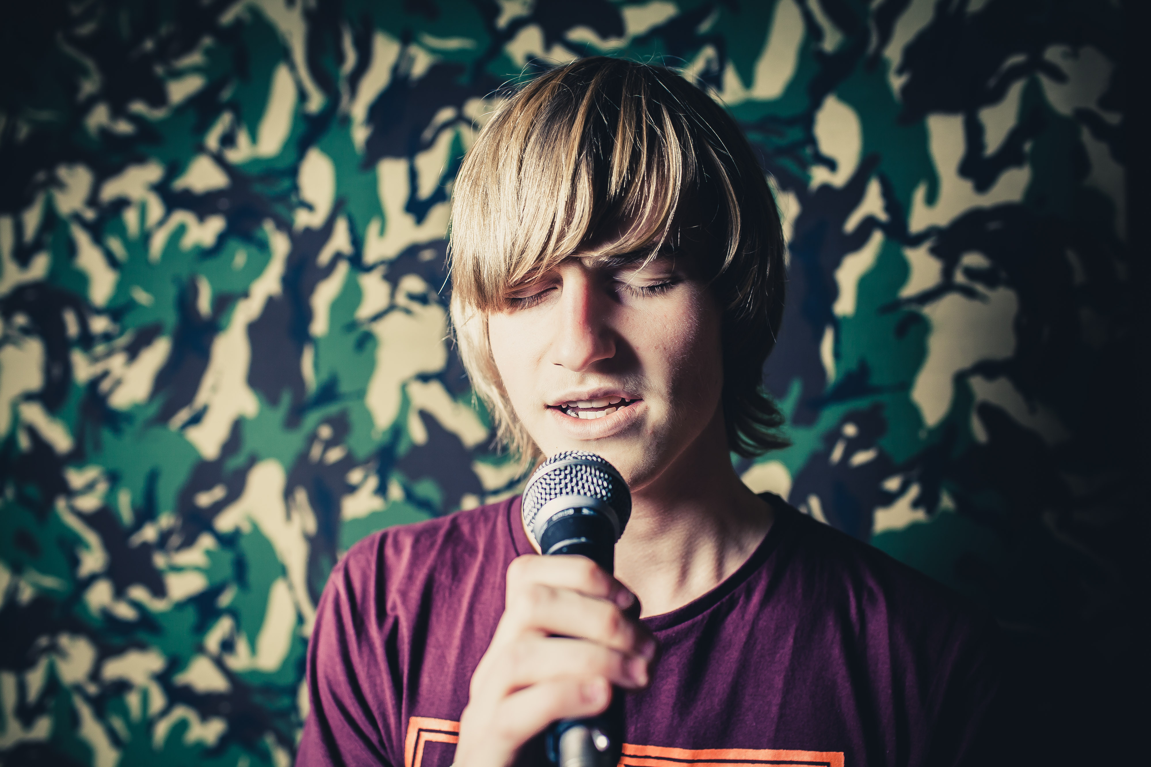 Young man with blonde hair singing into a microphone