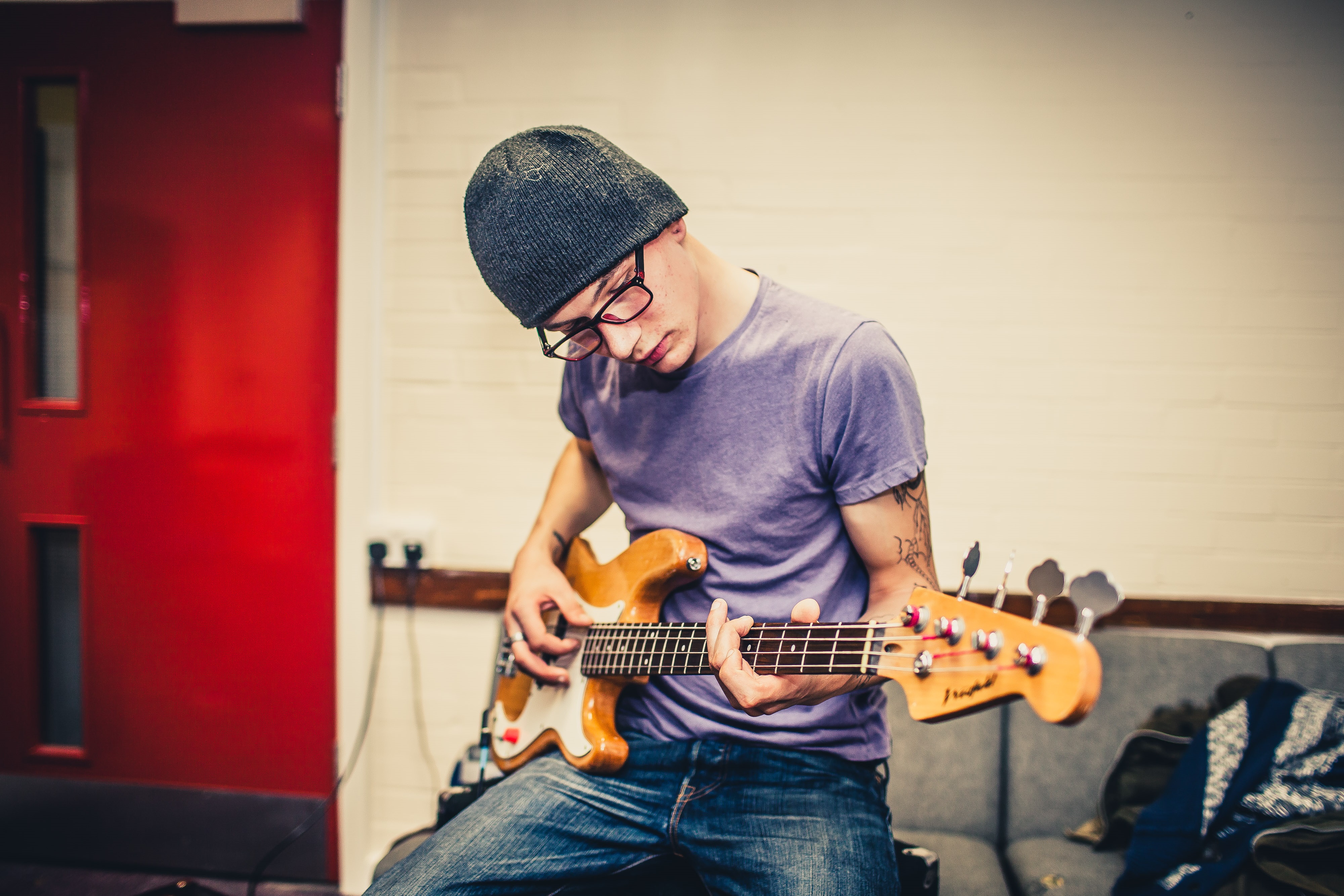 Young man wearing black beanie hat and blue t shirt playing guitar at Band Room