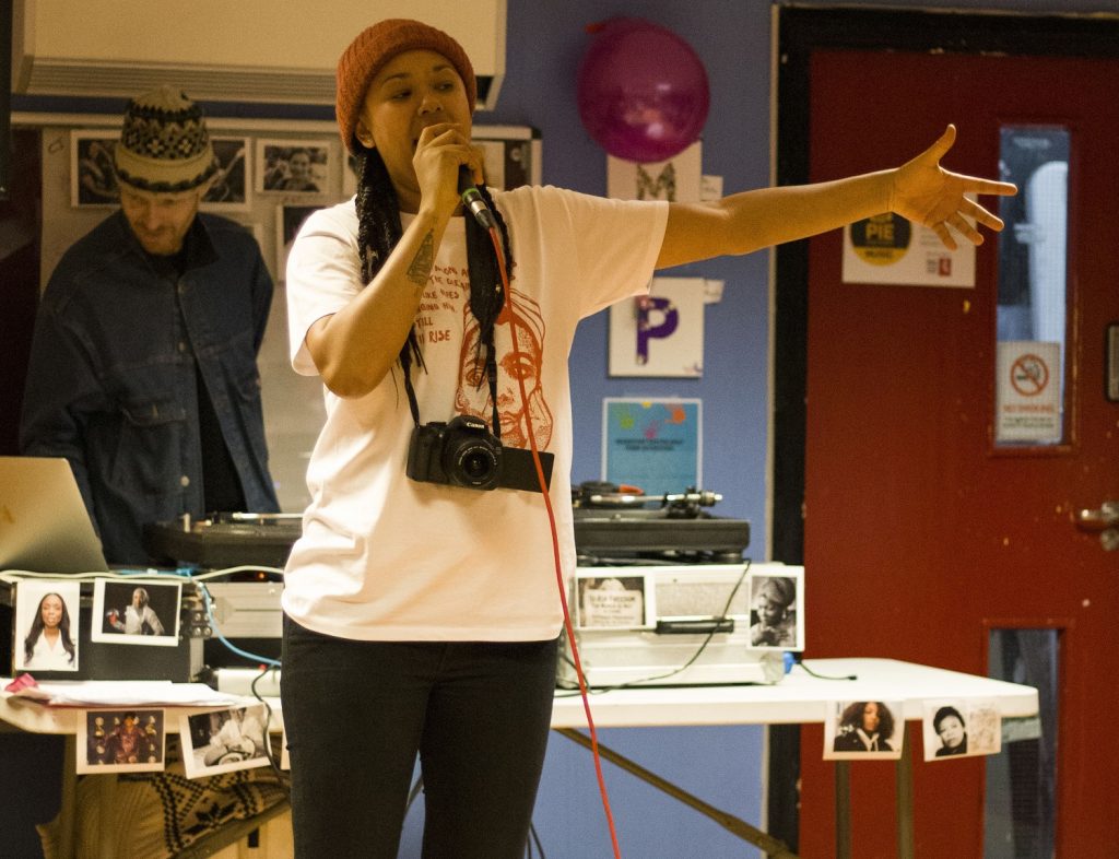 Band Room session with young person singing into microphone with one arm raised as they perform