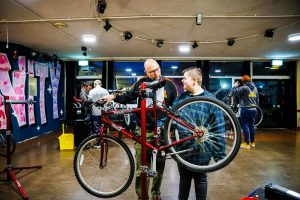 A Pie volunteer with a young person in the youth club fixing a bike and talking to each other