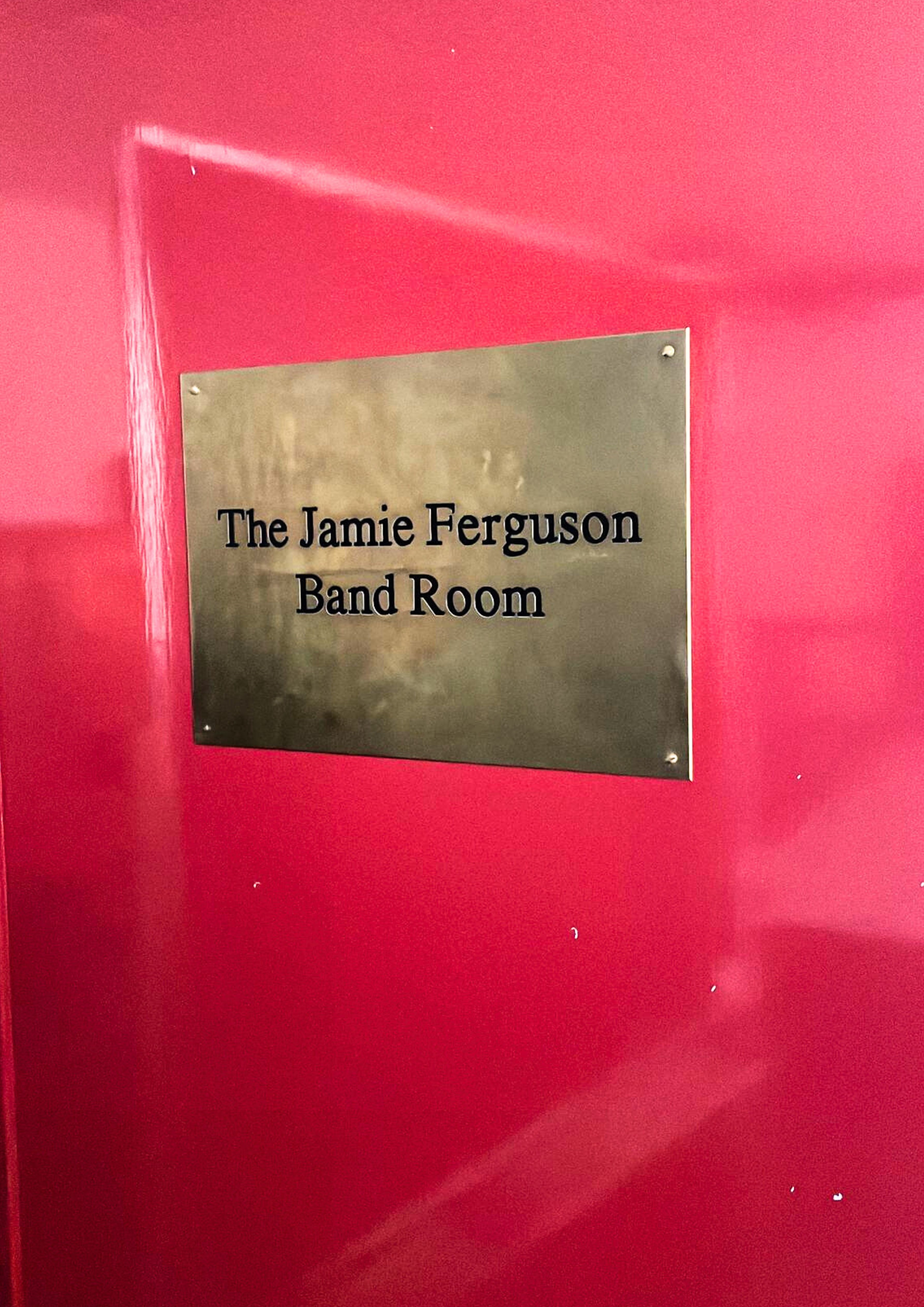 A gold plaque on a red door in tribute to Jamie Ferguson